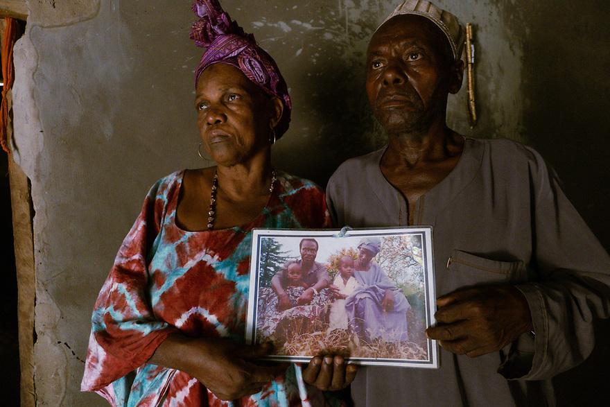 Candé’s parents holding a family photo at their home